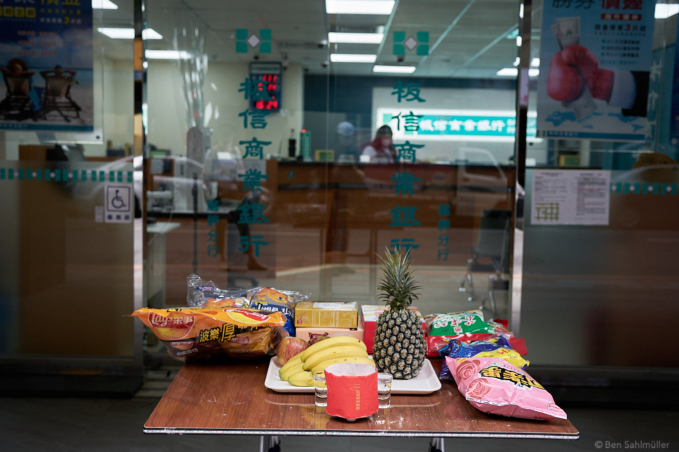 A small table with some food offerings in front of a small bank.